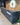 A reception desk clad in charcoal and black brick slips staggered around. Behind is wood cladding with a circular logo.