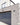 The front of a property- with the lower half clad in grey creased brick slips next to a navy garage door.