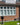 The front of a house, clad in red multi brick slips, with a white framed window, grass is in front of the property.