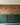 A red brick slip feature wall with sandy coloured mortar. The bottom half is covered with green panelling.