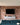 A bright reclaimed red brick feature wall with a central TV, and a wall unit underneath in grey.