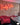 A reclaimed style brick slip wall with a neon sign saying 'funky vibes'. There is a pink velvet chez lounge in front.