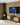 Yellow London Brick slips clad two adjoined walls, one has a large TV on, with a wooden unit underneath.