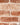 A close up of white pointing mortar on a red brick slip wall.